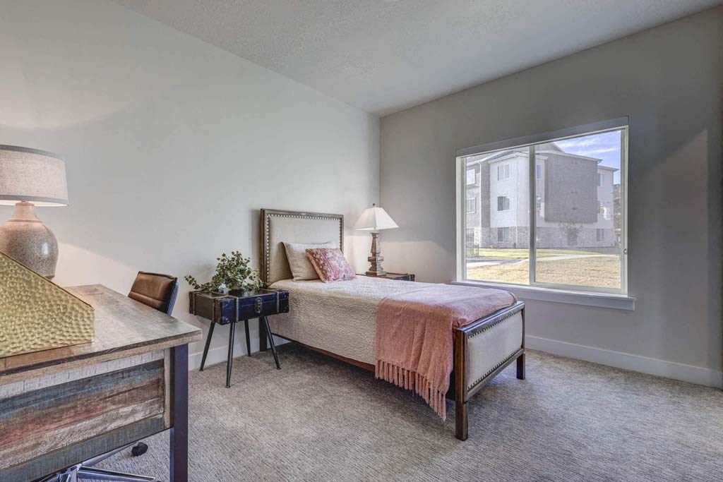 A bedroom with a bed, nightstand, and window.