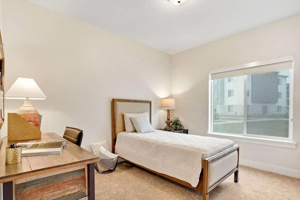 A bedroom with a bed, nightstand, and window.