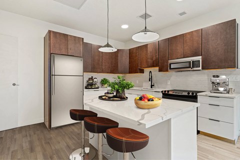 A kitchen with a white countertop and brown bar stools.
