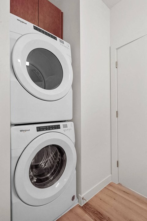 Two white Whirlpool washing machines stacked on top of each other.