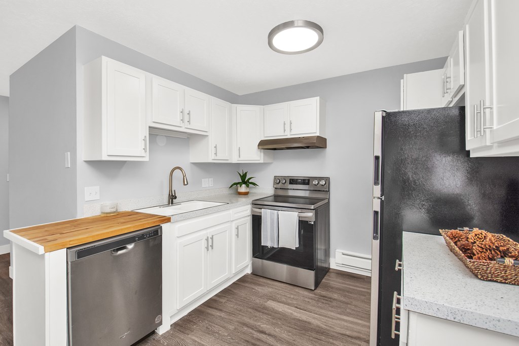 A modern kitchen with white cabinets and a wooden countertop.
