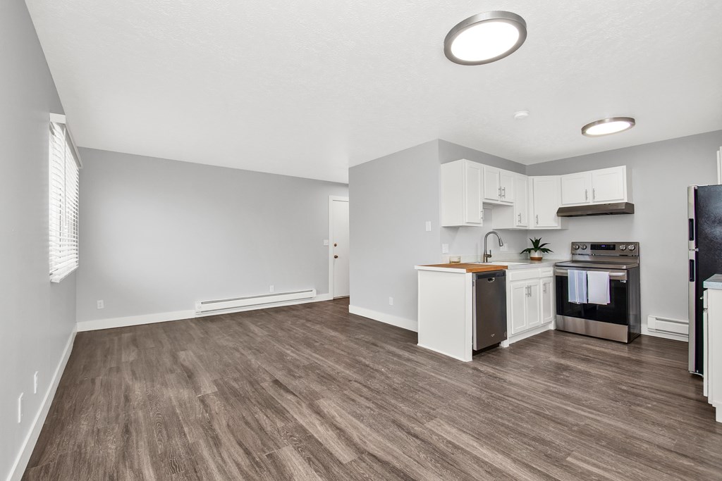 A kitchen with white cabinets and a wooden floor.