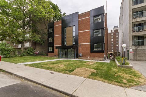 A modern building with a black and brown facade is situated on a street corner.