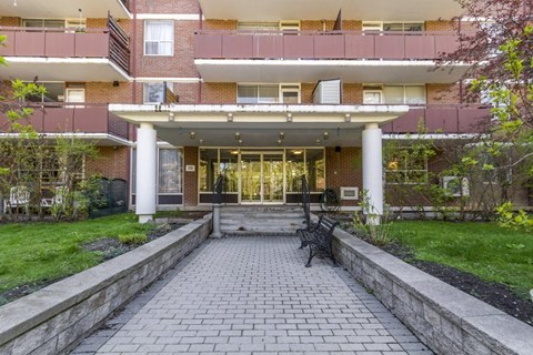 A brick building with a covered walkway leading to the entrance.