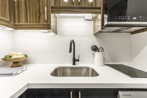A modern kitchen with a stainless steel sink and wooden cabinets.