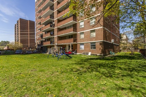 A grassy area in front of a brown brick apartment building.