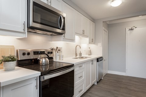 A kitchen with white cabinets and black countertops.