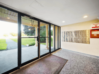 A hallway with a red carpet and a glass door.