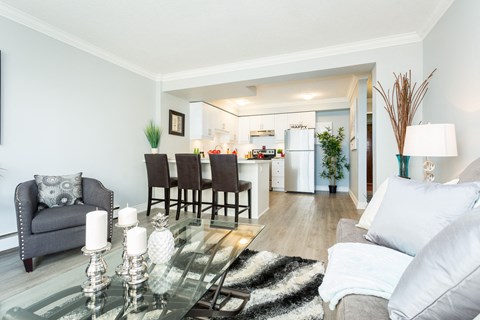 A modern living room with a glass coffee table and a grey sofa.