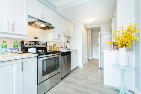 A kitchen with white cabinets and a stove top oven.