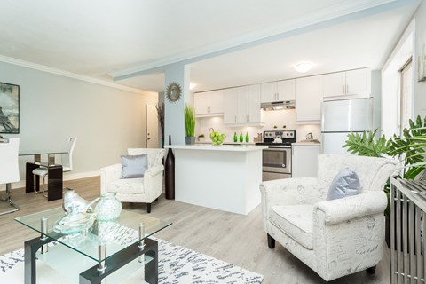 A modern living room with a glass coffee table and two white armchairs.
