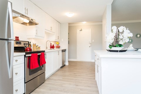 A kitchen with white cabinets and a stainless steel refrigerator.