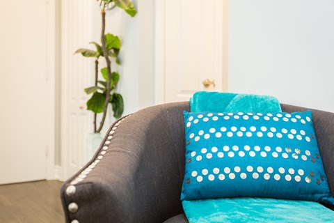 A grey couch with a blue pillow and a blue cushion on it.