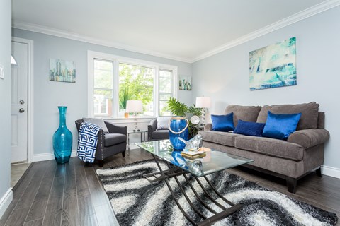 A living room with a grey couch and a glass coffee table.
