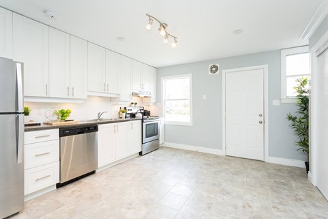 A kitchen with white cabinets and a stainless steel refrigerator.