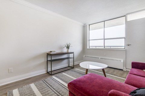 A living room with a red chair and a white table.