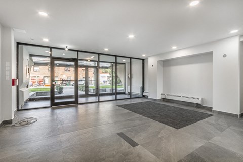A spacious room with a grey tiled floor and a large window with a view of the outside.