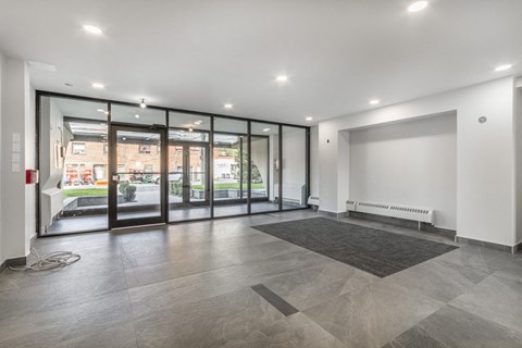 A spacious room with a grey tiled floor and a large window with a view of the outside.