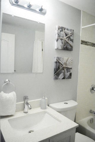 A white bathroom with a sink, toilet and mirror.