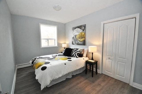 A bedroom with a bed, a small table with a lamp, and a painting on the wall.