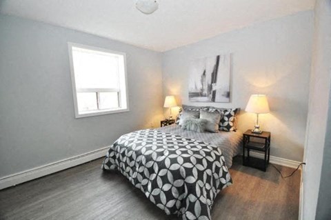 A bedroom with a bed, nightstand, and lamp.