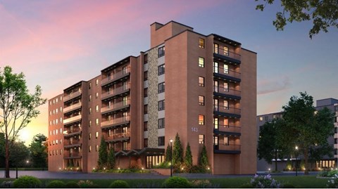 A large apartment building with balconies and lights on the ground floor.