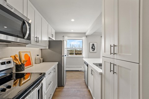 A modern kitchen with white cabinets and stainless steel appliances.
