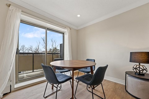 A dining room with a table and chairs and a view of the outside.