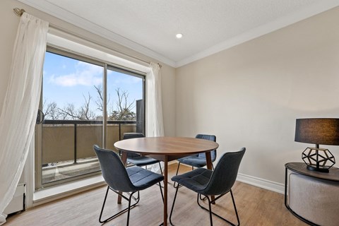 A dining room with a table and chairs and a view of the outside.