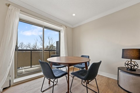 A dining room with a table and chairs and a view of the outside.