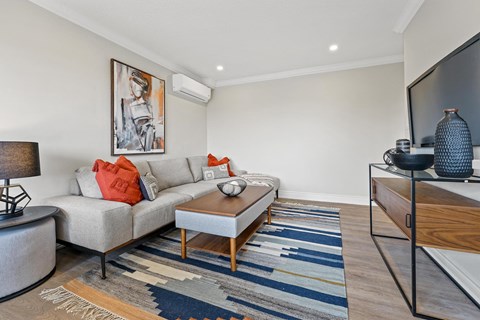 A living room with a grey couch, a coffee table, and a painting on the wall.