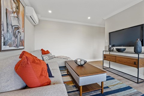 A living room with a grey couch, a coffee table, and a painting on the wall.