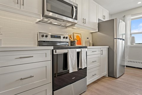 A modern kitchen with white cabinets and stainless steel appliances.