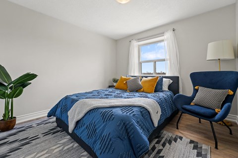 A bedroom with a blue bedspread and a blue chair.