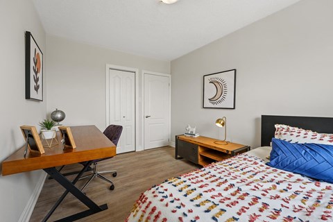 A bedroom with a bed, desk, and chair.