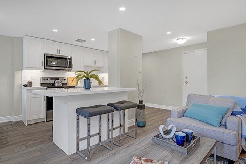 A modern kitchen with white cabinets and a bar area.