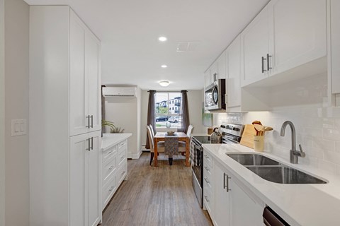 A kitchen with white cabinets and a wooden floor.