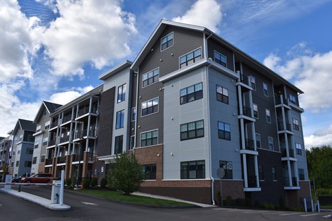 A large apartment building with a parking lot in front.