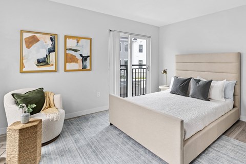 a bedroom with a bed and a chair and a door to a balcony