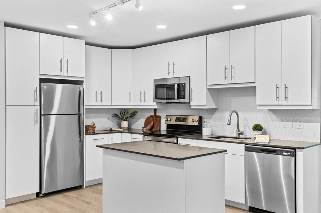 an all white kitchen with stainless steel appliances and white cabinets