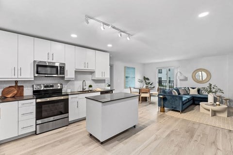 an open kitchen and living room with white cabinets