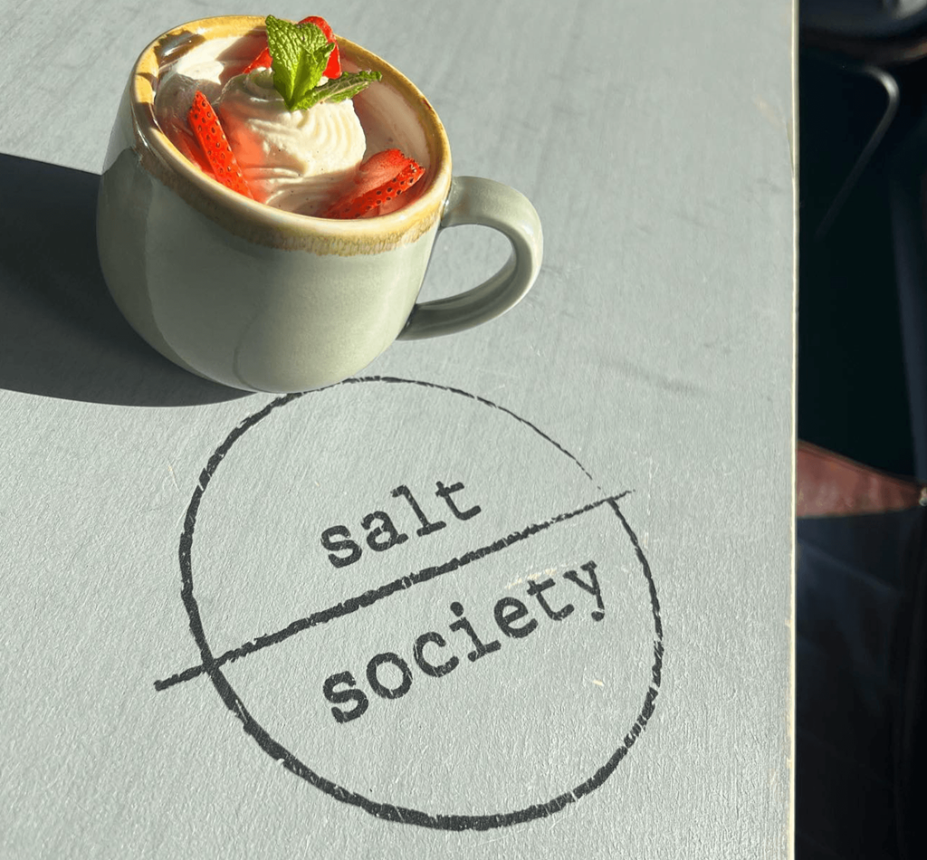 a cup of coffee on a table with the word salt society