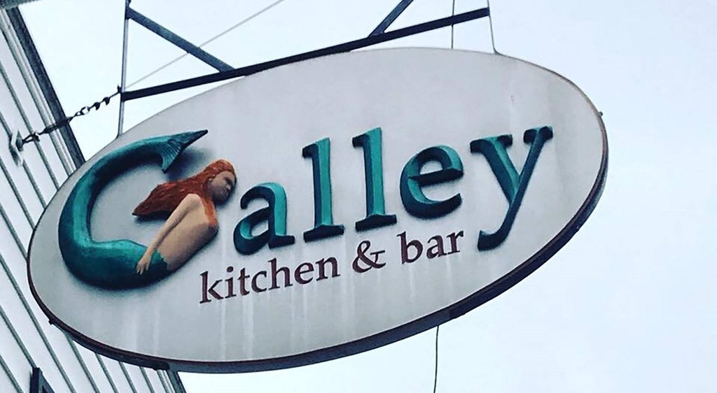 a sign for alley kitchen and bar on a building