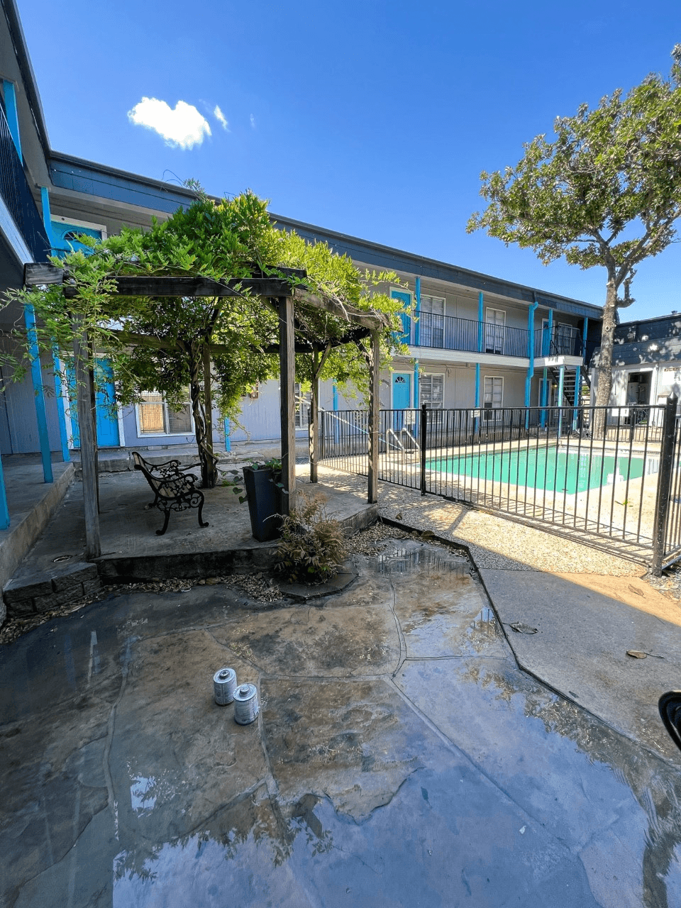 a courtyard with a bench and a gazebo with a tennis court in the background