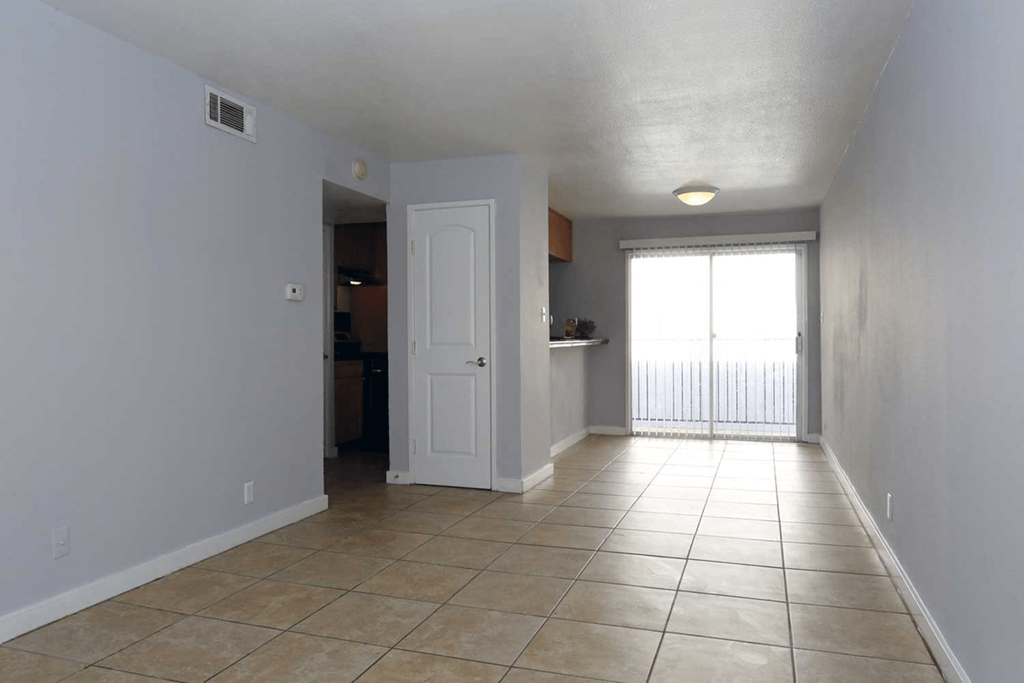 a large room with a tiled floor and a door that leads to a kitchen