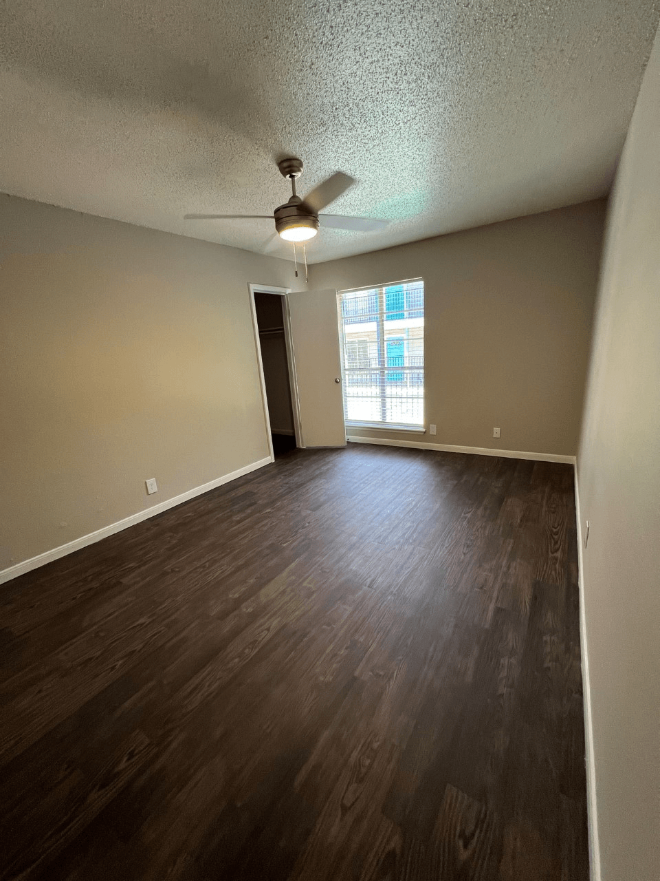 an empty living room with a window and a ceiling fan
