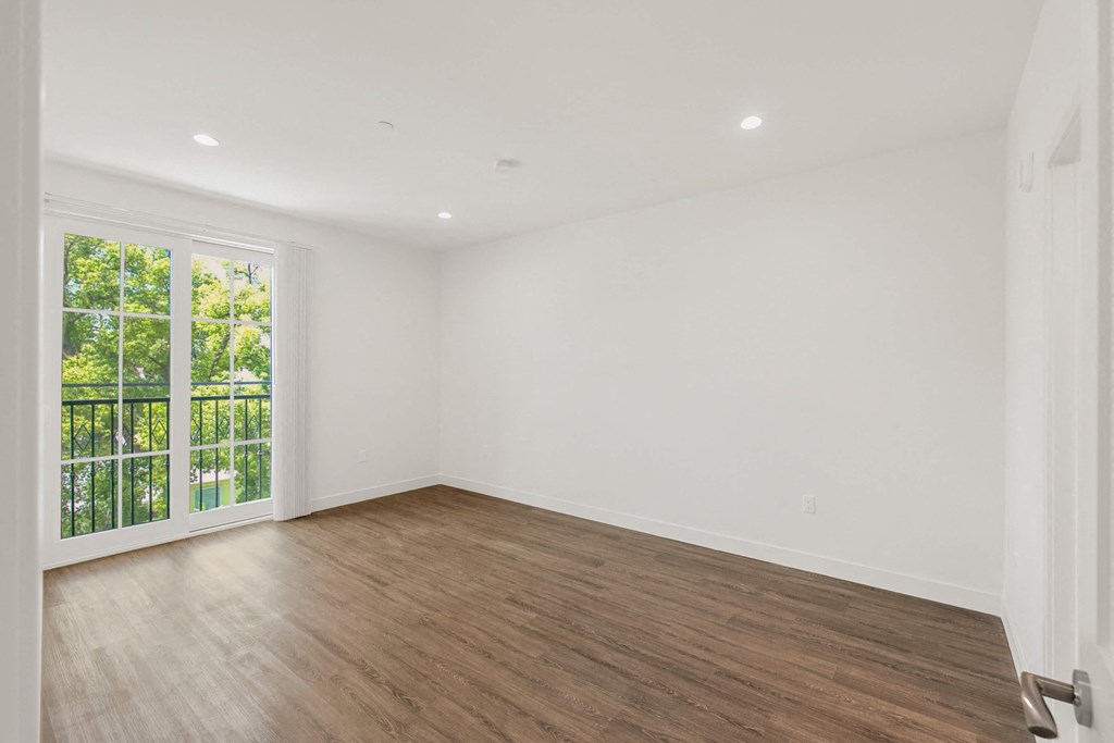 a bedroom with hardwood floors and white walls