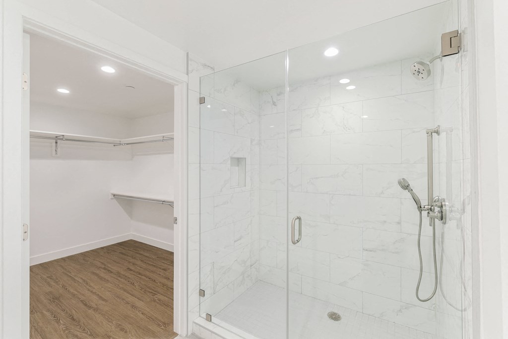 a bathroom with a glass shower stall and wood flooring