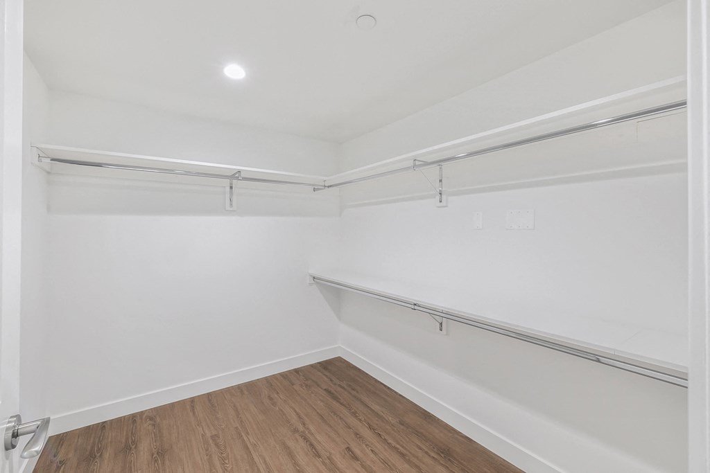 a spare room with white walls and wood flooring