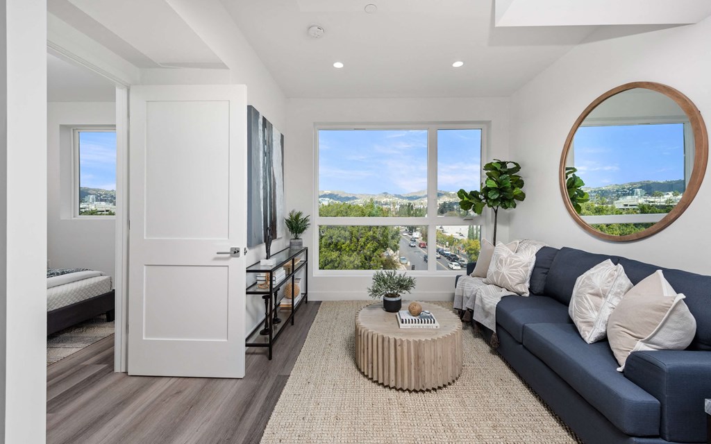 a living room with a blue couch and a round coffee table in front of a large window
